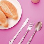 a plate of food and a fork on a pink table