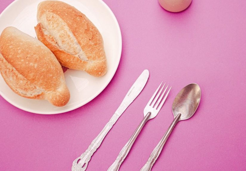a plate of food and a fork on a pink table