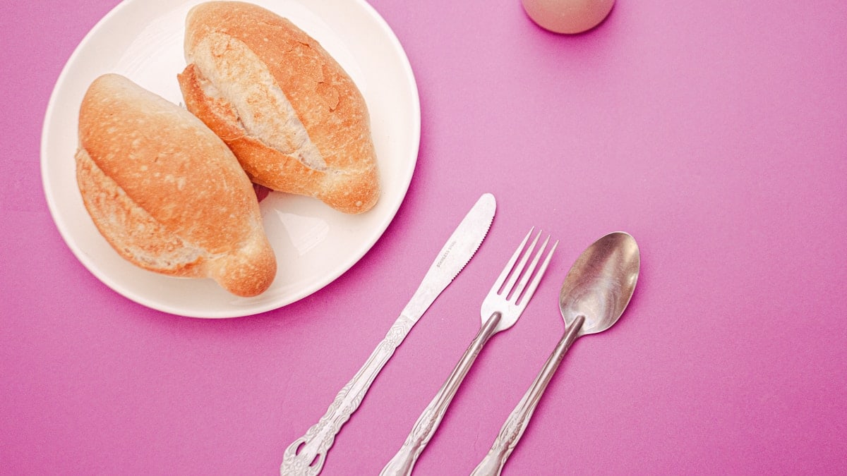 a plate of food and a fork on a pink table