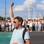 man in white and black crew neck t-shirt raising his right hand