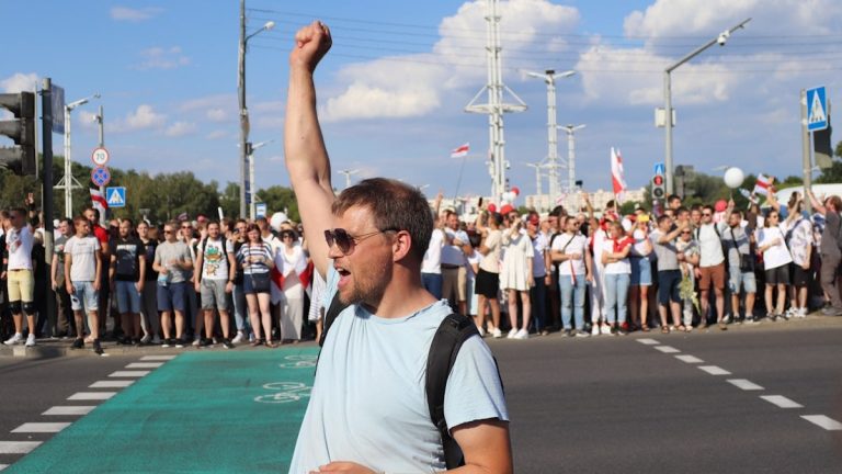 man in white and black crew neck t-shirt raising his right hand