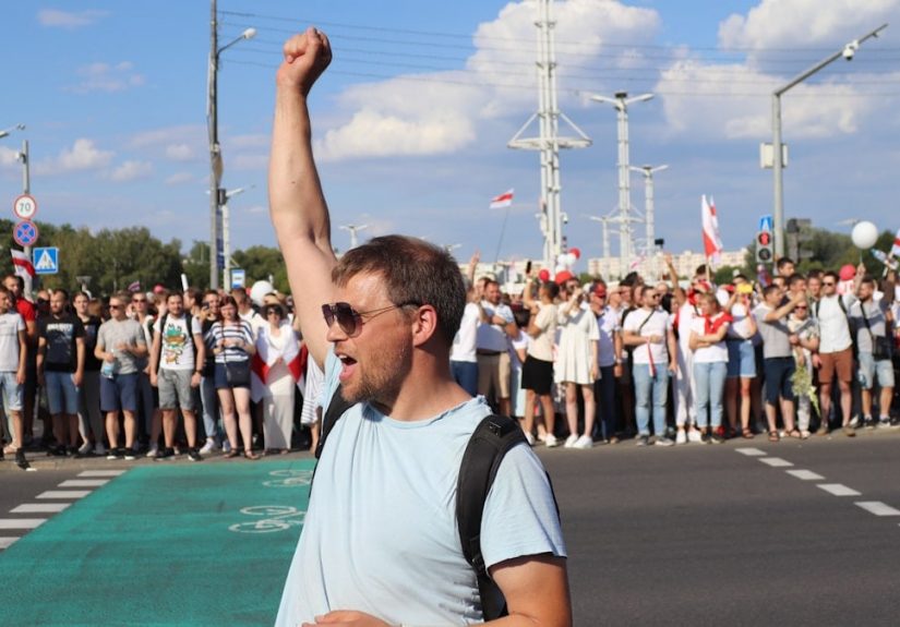 man in white and black crew neck t-shirt raising his right hand